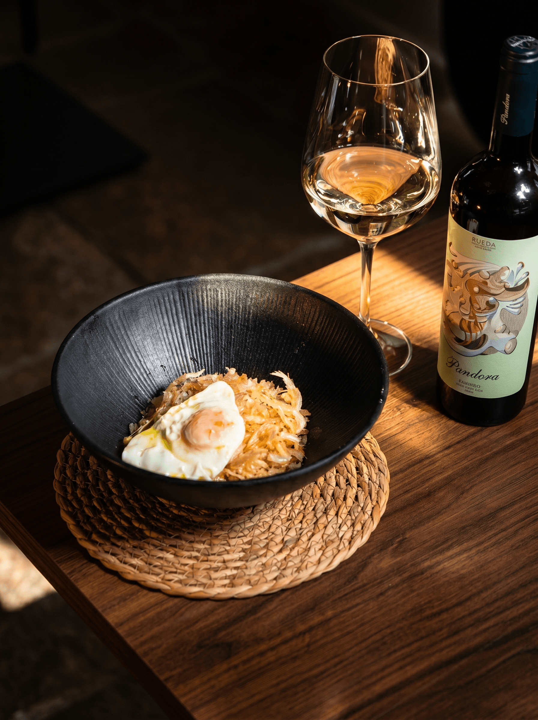 Fried egg with a whole runny yolk over a crisp fry, in a black bowl · Acontramar, La Herradura