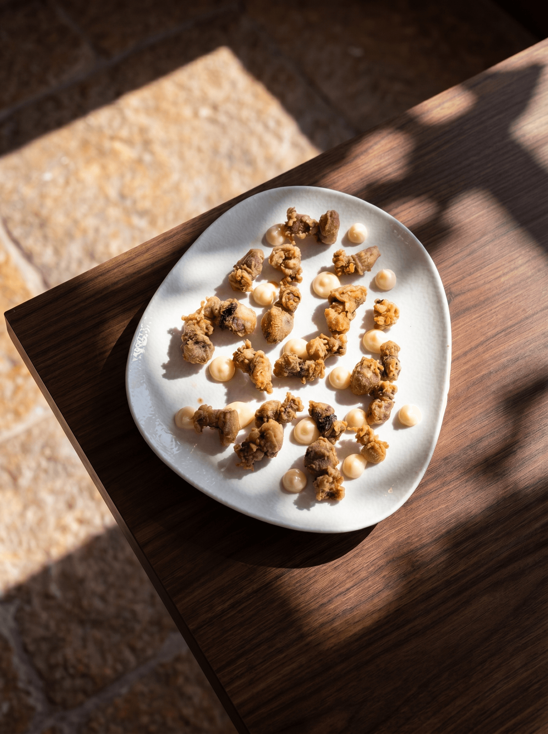 Fried baby squid with dots of aioli, on a white plate · Acontramar, La Herradura